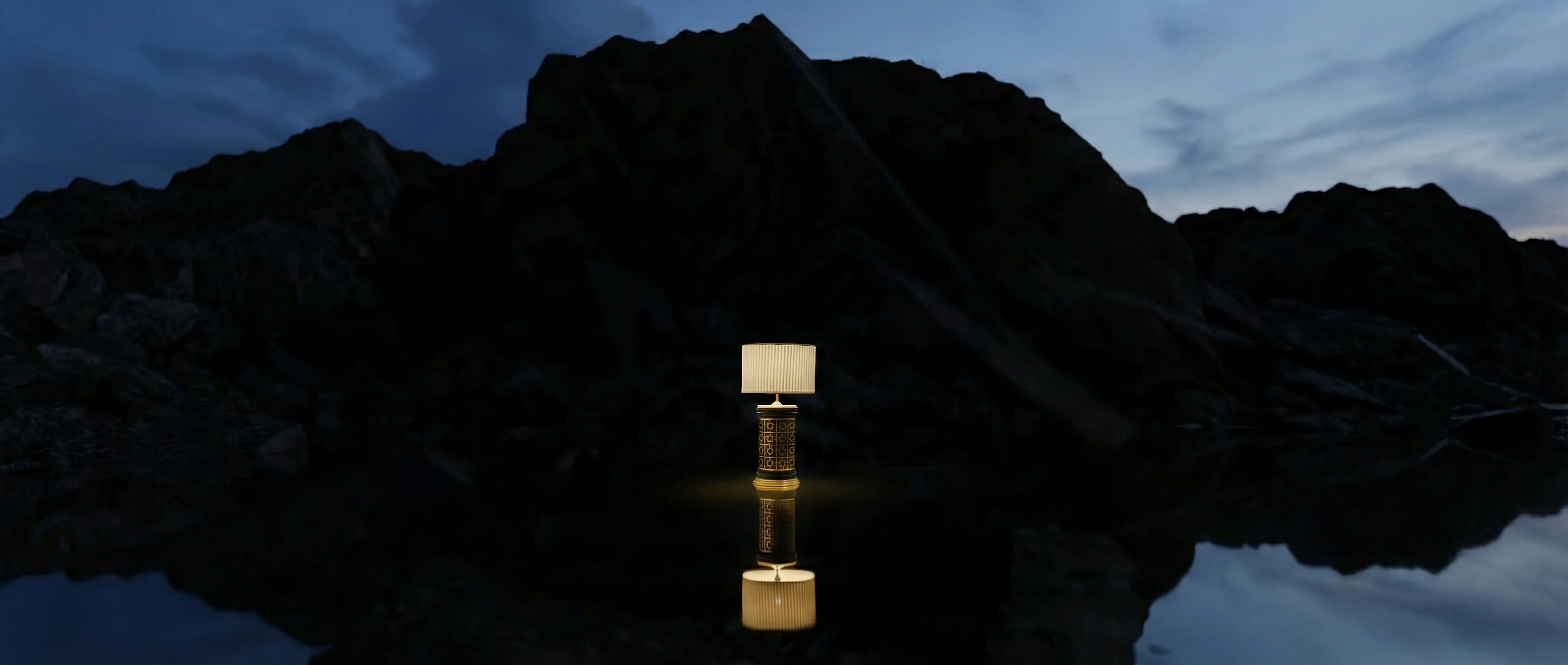 Gallery interior view with warm lighting, framed artwork on walls, and decorative lamp